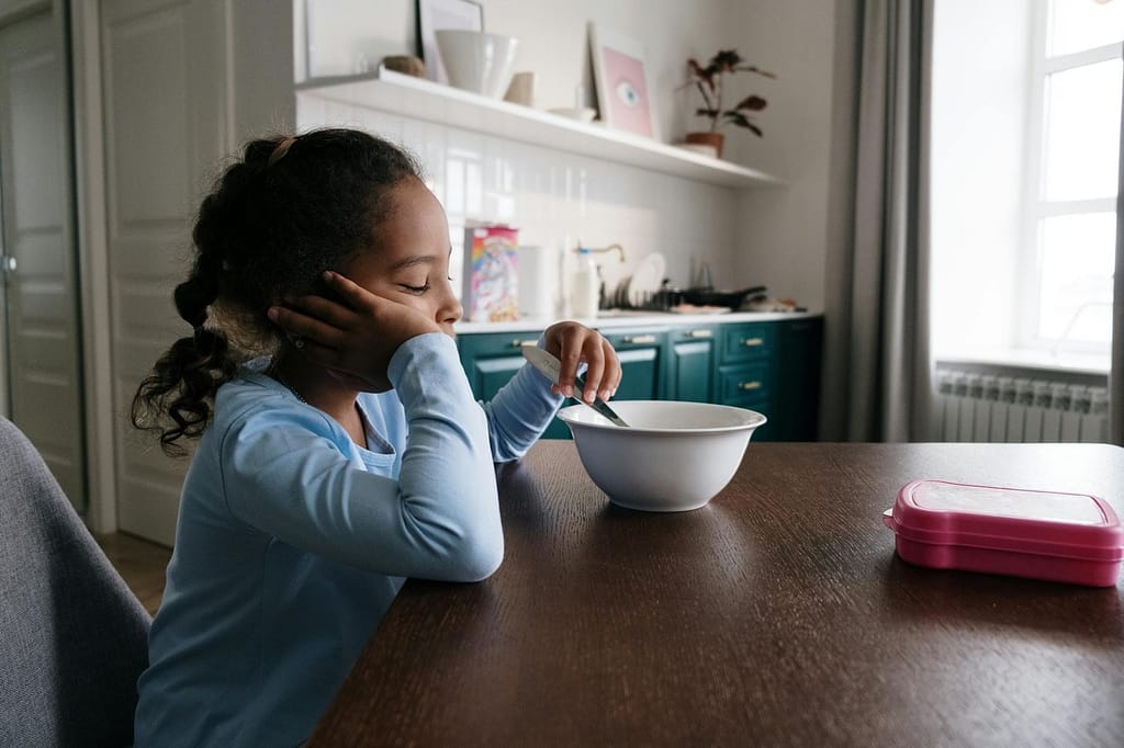 girl in blue long sleeve shirt holding silver utencil