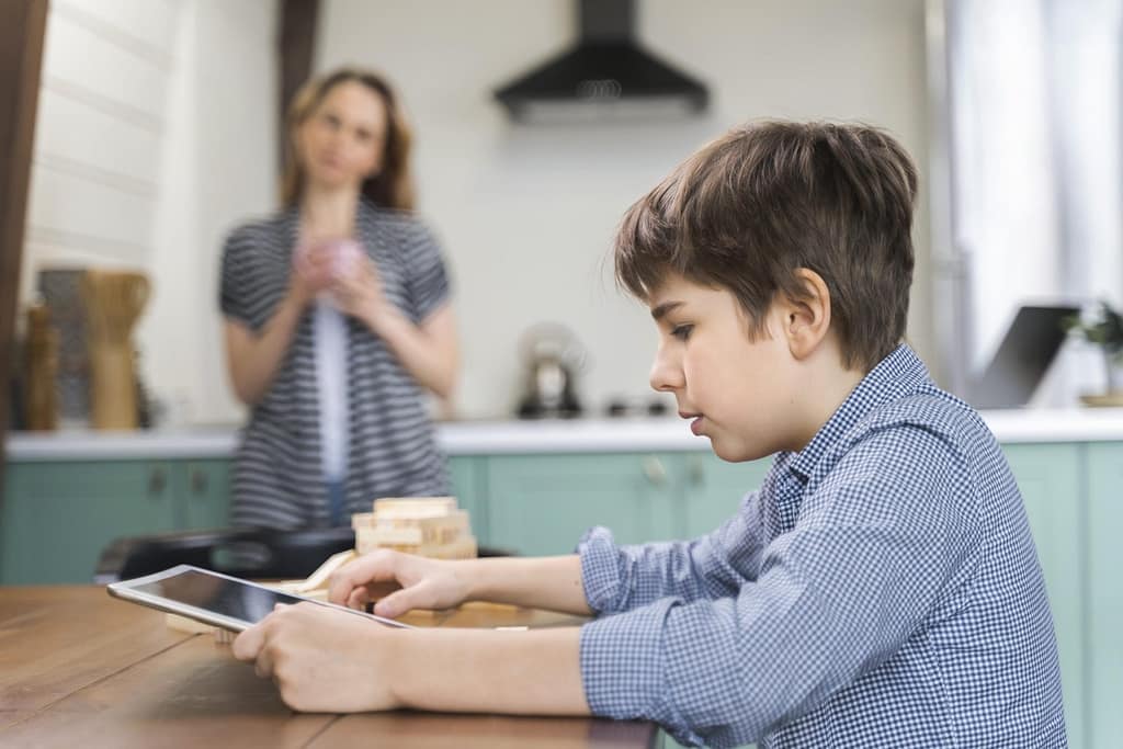 Parent guiding child to use screens responsibly at home while controlling screens
